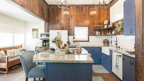 A kitchen with a central island, blue cabinets, wooden accents, and pendant lighting. - Historic Gem in Virginia City (Virginia City)
