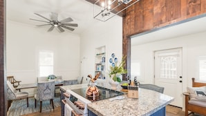 A kitchen with a central island, a ceiling fan, and a dining area with patterned chairs. - Historic Gem in Virginia City (Virginia City)