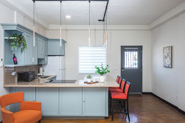 A modern kitchen with a central island, built-in appliances, and a dining area with chairs.