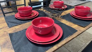 A dining table with red plates and bowls, black placemats, and a black chair in the background. - Charming 2-bedroom townhome - All brand new - pets welcome (Sacramento)