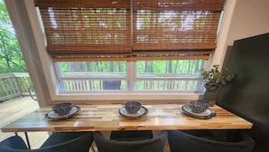 A wooden table with three black chairs and a window with bamboo blinds. - Charming 2-bedroom cabin in delightful New Market with AC (New Market)