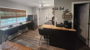 A modern kitchen with a bar area, a coffee station, and a dining space with bar stools. - Charming 2-bedroom cabin in delightful New Market with AC (New Market)