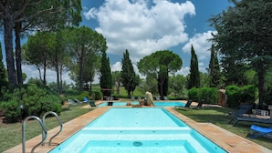 A rectangular swimming pool with a tiled deck, surrounded by lounge chairs and trees. - Podere Delle Vigne, in the Vineyards of Maremma (Grosseto)