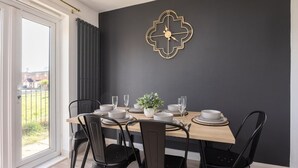 Un comedor con una pared oscura, un reloj geométrico y vistas al exterior.