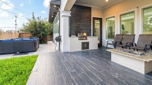 Une terrasse extérieure moderne dotée d’un barbecue intégré, d’un espace salon et d’un jacuzzi.