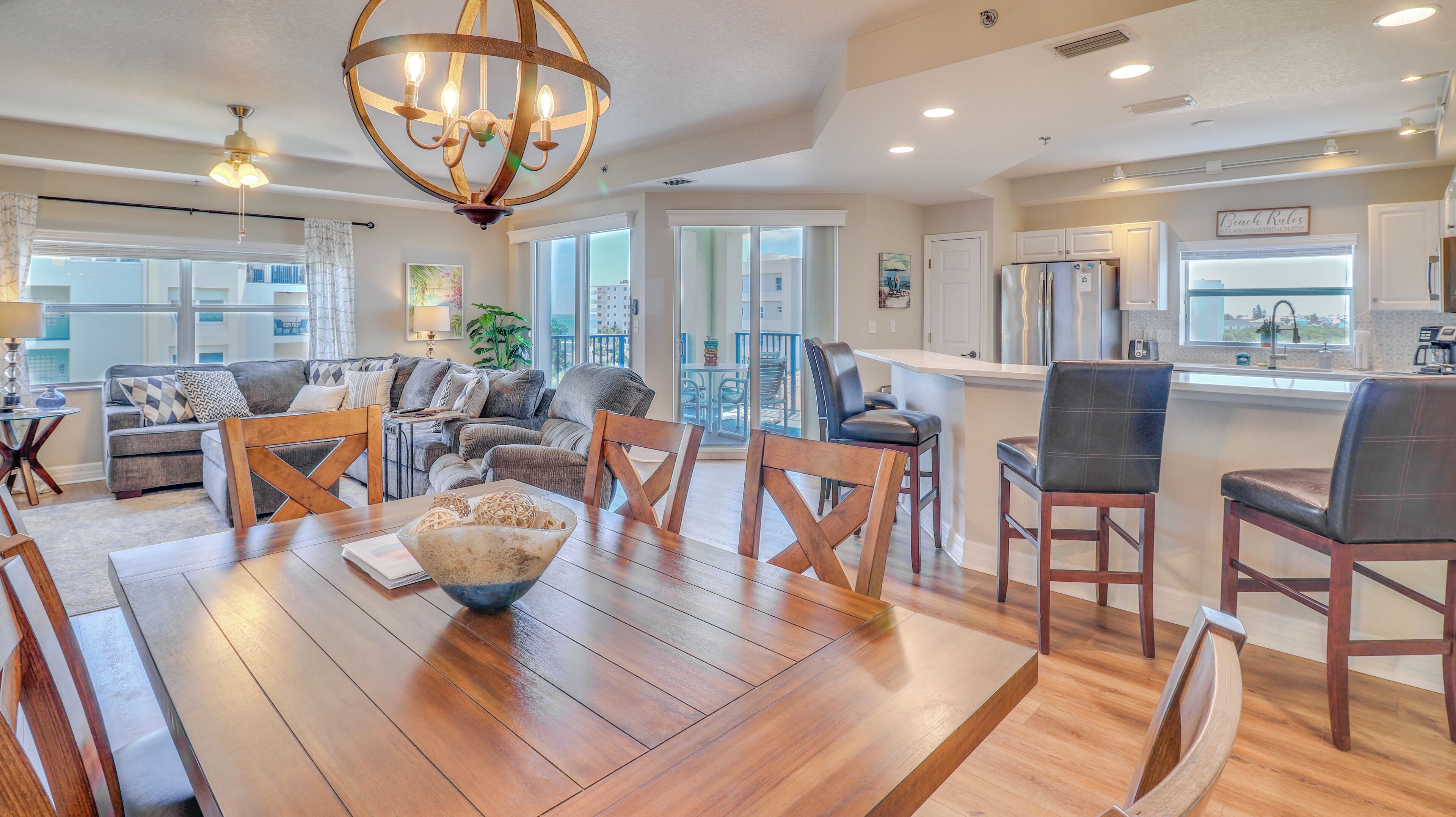 A spacious living area with a wooden dining table, comfortable seating, and a large chandelier.