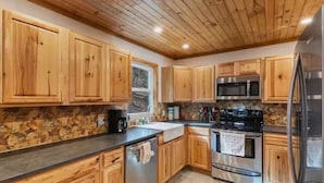 Una cocina con armarios de madera, un refrigerador de acero inoxidable, un microondas y una estufa.
