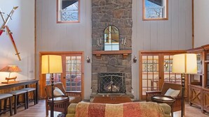 Una sala de estar acogedora con chimenea de piedra, muebles de madera y ventanas amplias.
