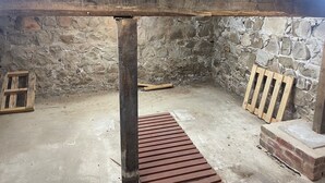Et rum med stenvægge, loftsbjælker i træ, beton gulv og en sokkel af mursten.