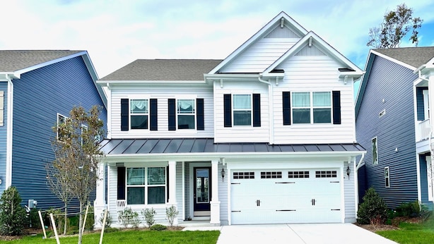 A two-story residential building with a garage, a front porch, and a small front yard with young trees. - Delaware getaway near Bethany Beach (Ocean View)