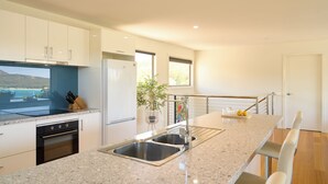 A modern kitchen with a granite countertop, stainless steel sink, and built-in oven. - Deja Blue 1 - Freycinet (Glamorgan-Spring Bay)