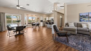 A spacious living area with a dining table, a sofa, and a kitchen in the background. - Sun and Shade Oasis  by J and Amy BL 991449 (Mesquite)