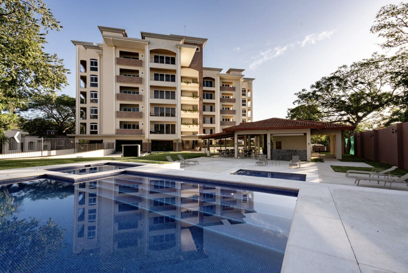 Un hôtel moderne doté d’une grande piscine extérieure, de nombreux balcons et d’un patio couvert.