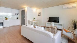 Una sala moderna con un sofá blanco, una mesa de comedor y un televisor.