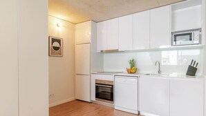 Una cocina compacta con armarios blancos, horno empotrado, lavavajillas y microondas.