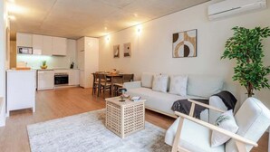 Een moderne woonkamer met een bank, een bijzettafeltje en een eethoek op de achtergrond.
