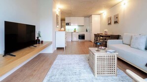 Een moderne woonkamer met een flatscreen televisie, een houten salontafel en een bank.