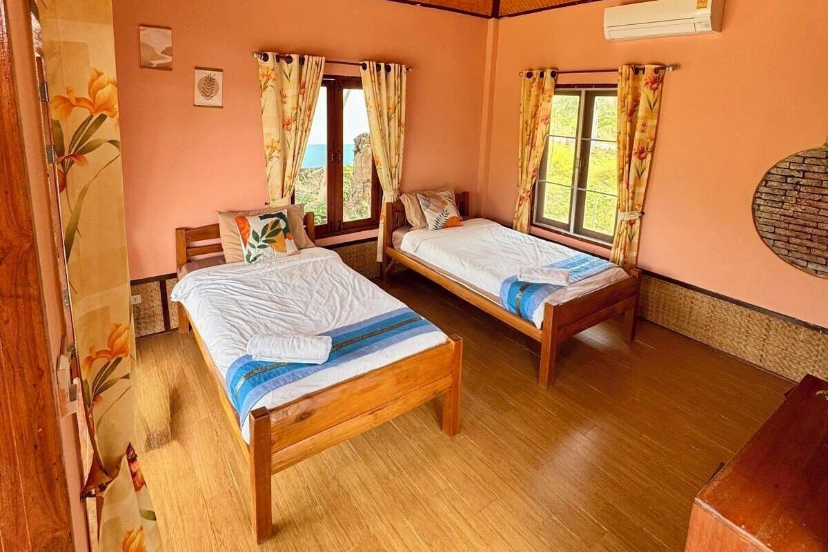 A room with two wooden beds, a ceiling fan, and an air conditioning unit.