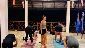 A group of people on yoga mats in a covered outdoor area with a metal roof and hanging decorations. - The Nest Pai Love Resort (Pai)