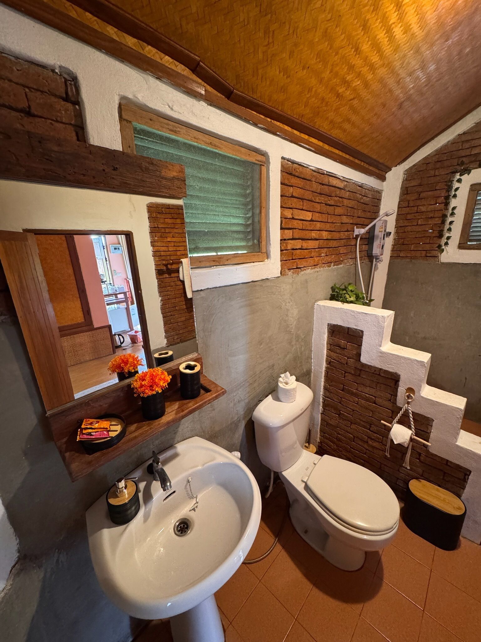 A bathroom with a wooden ceiling, a window, a sink, a toilet, and a shower.