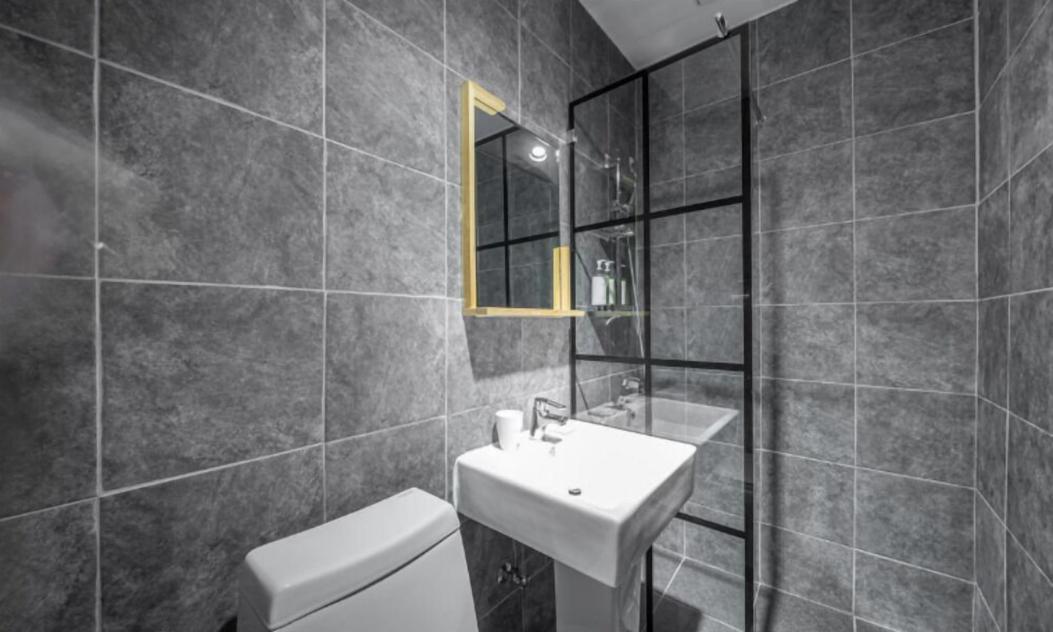 Un baño moderno con inodoro, lavamanos y cabina de ducha de vidrio.