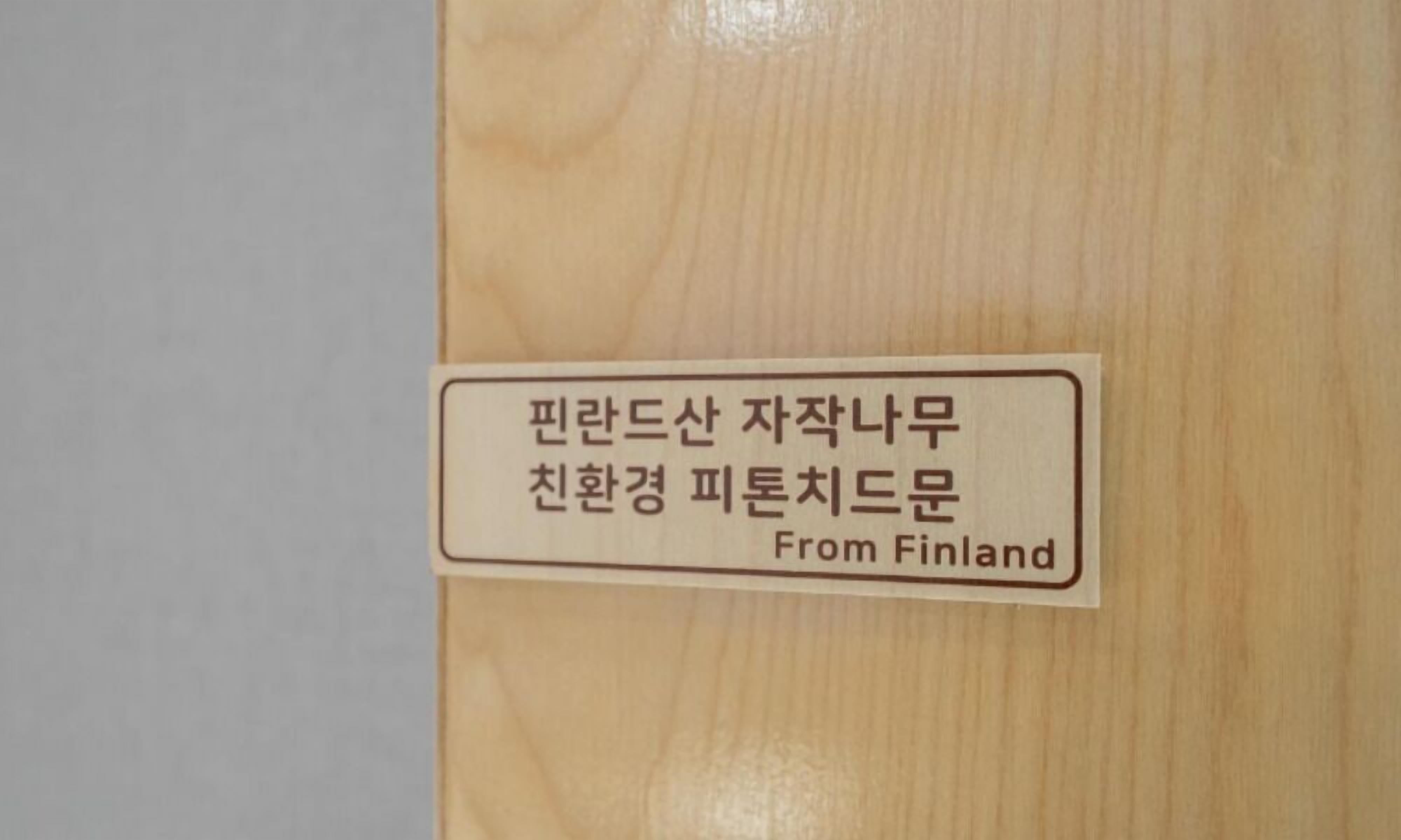 Una puerta de madera con una etiqueta que dice "Finlandia" y texto en coreano.