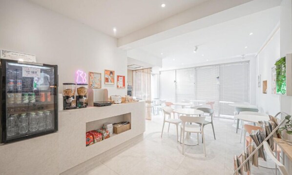 A modern hotel lobby with a reception desk, seating area, and a refrigerator stocked with beverages. - POHANG VILLA DAHLIA (Pohang)