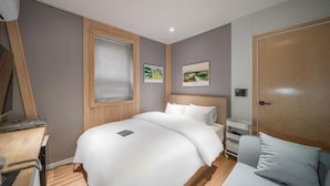 Un dormitorio con cama, mesita de noche y escritorio con silla.
