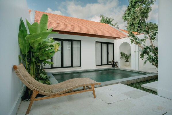 A poolside area with a lounge chair, a small pool, and potted plants. - Avura Villa Munggu (Munggu)