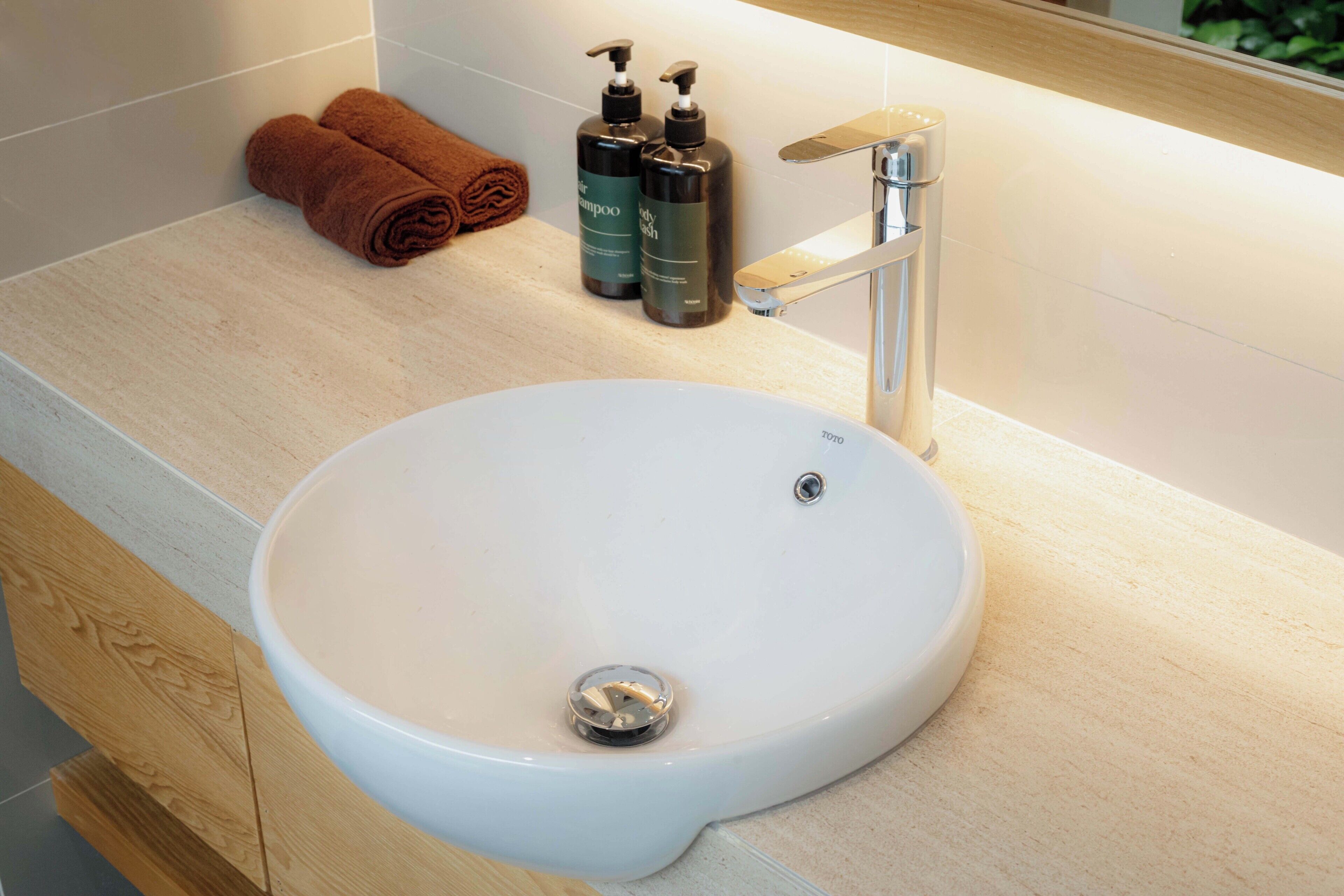 Un baño con un lavamanos blanco, un grifo moderno y dos botellas de champú.