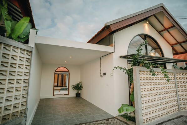 Una casa moderna con ingresso piastrellato, un'ampia porta ad arco e un portico coperto.