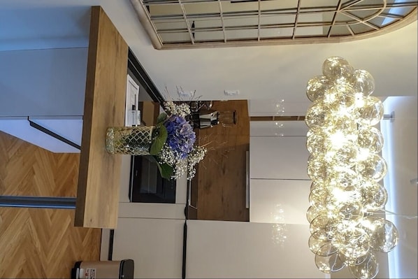 Et moderne køkken med en unik lysekrone, trædetaljer og en dekorativ vase med blomster.