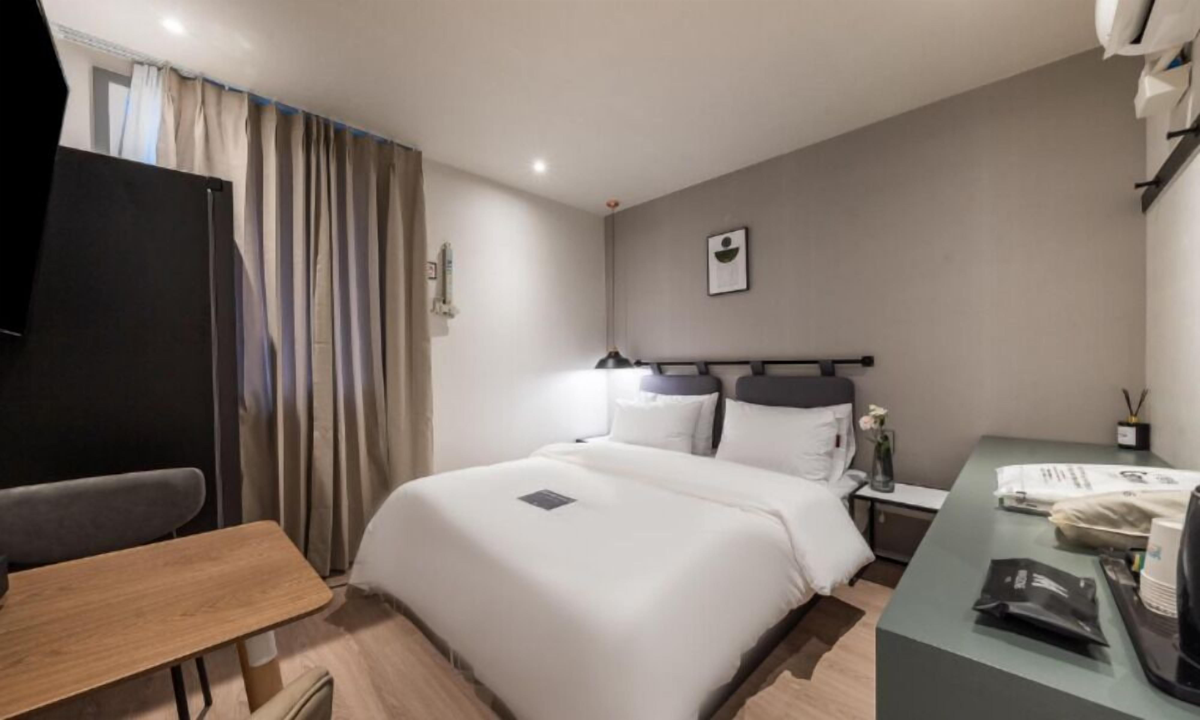 Una camera d'albergo con un letto, un comodino e una scrivania con una sedia.