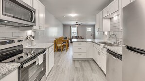 A modern kitchen with white cabinetry, granite countertops, a built-in oven, and a dishwasher. - Country cozy with beach bless (Bolivia)
