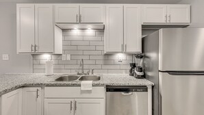 A modern kitchen with white cabinets, a stainless steel refrigerator, a dishwasher, and a double sink. - Country cozy with beach bless (Bolivia)