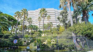 A hotel with a modern design, featuring a large building with multiple balconies and surrounded by lush greenery and palm trees.