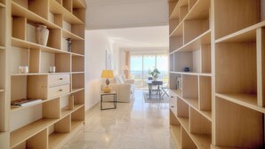 A spacious living area with high wooden shelving units, a sofa, a coffee table, and a view through a glass door to the outdoors.