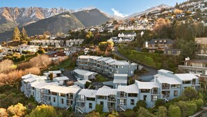 A modern residential area with multi-story buildings, a winding road, and a mountainous backdrop.