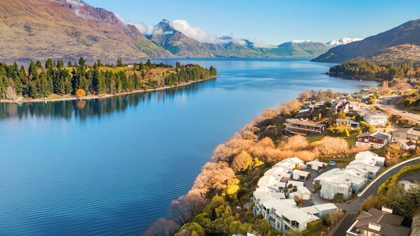 A lakeside residential area with modern houses, a clear view of the lake, and mountainous terrain in the background.