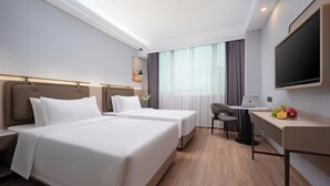A hotel room with two beds, a desk with a laptop, a flat-screen TV, and a small table with fruit. - Shenzhen Nanshan Yuetu Hotel (Shenzhen)