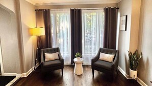 Un salon avec deux fauteuils sombres, une table basse ronde et une lampe.