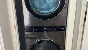 Une machine à laver et un sèche-linge superposés dans un couloir étroit.