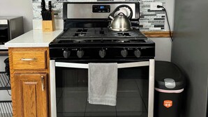 Une cuisine dotée de meubles en bois, d’une hotte en acier inoxydable, d’une cuisinière à gaz et d’un four encastré.
