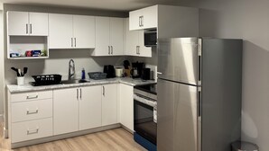 Een moderne keuken met witte kasten, roestvrijstalen apparatuur en een houten vloer.