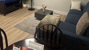 Een woonkamer met een televisie, een ventilator, een salontafel, een bank en een stoel.
