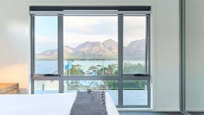Ein Schlafzimmer mit einer großen Schiebeglasdoor zum Balkon mit Blick auf die Berge.