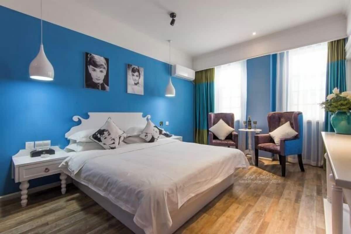 Una habitación de hotel moderna con una cama grande, dos sillas, una mesita y un escritorio.