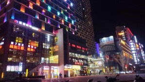 A multi-story hotel with illuminated signage and a modern architectural design. - Qing Niao Yi Shu Hotel (Kunming)