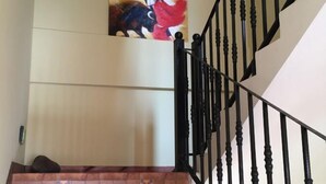 A staircase with a black iron railing and a tiled wall. - Qing Niao Yi Shu Hotel (Kunming)