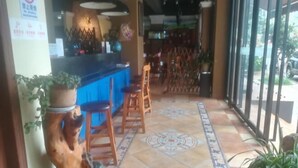 A restaurant interior with a counter, stools, and a patterned floor. - Qing Niao Yi Shu Hotel (Kunming)